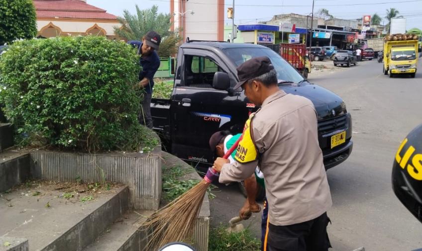 Wujudkan Lingkungan Bersih, Bhabinkamtibmas Bersama Perangkat Desa Gotong Royong Bersihkan Bundaran Giri Kencana